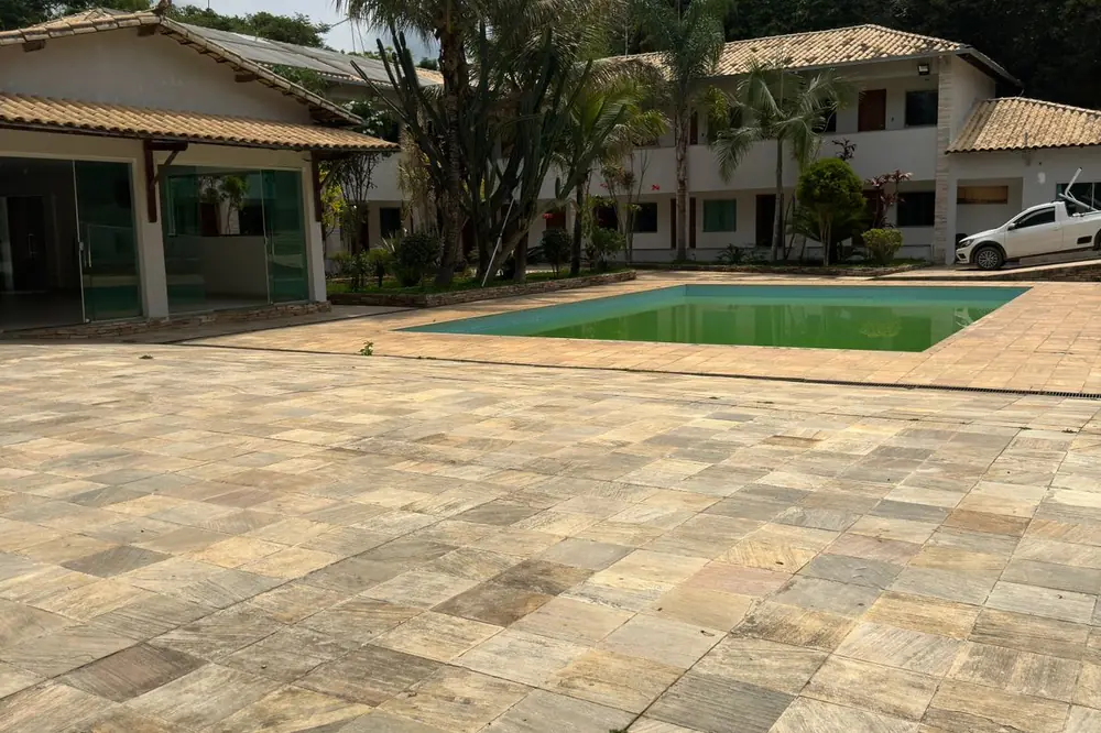 Área externa com piscina e piso de pedra ao lado dos alojamentos